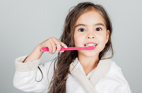 Young girl brushing her teeth with lessons learned from Cambridgeside Dental Associates in Cambridge, MA